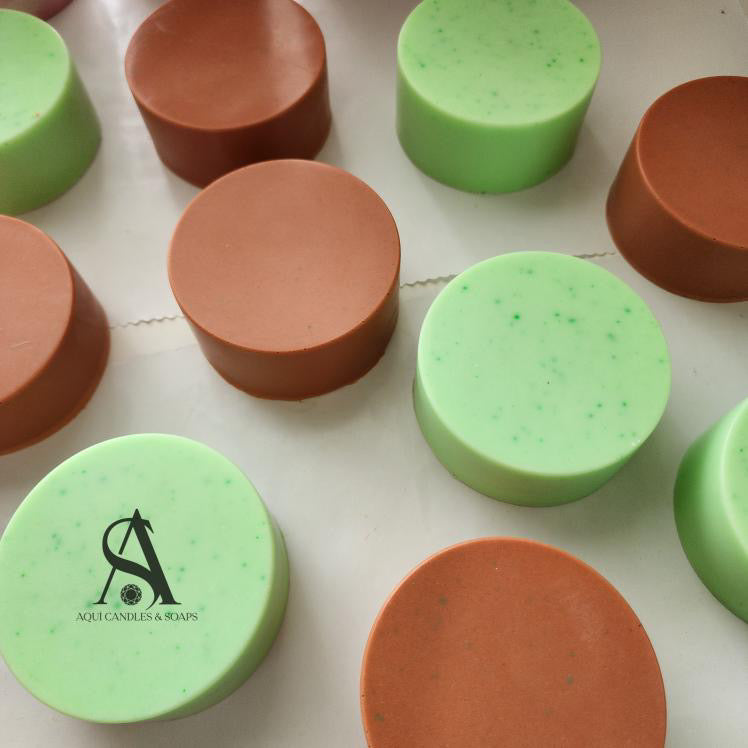Green and brown cylindrical soap with a visible brand logo on a light background