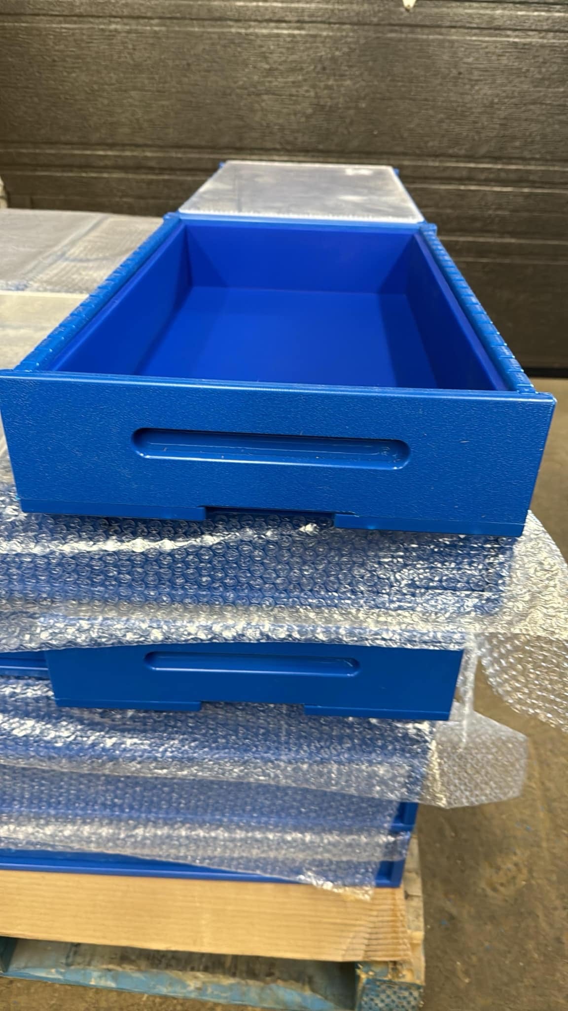 Stack of blue high density plastic soap molds on a pallet with bubble wrap.