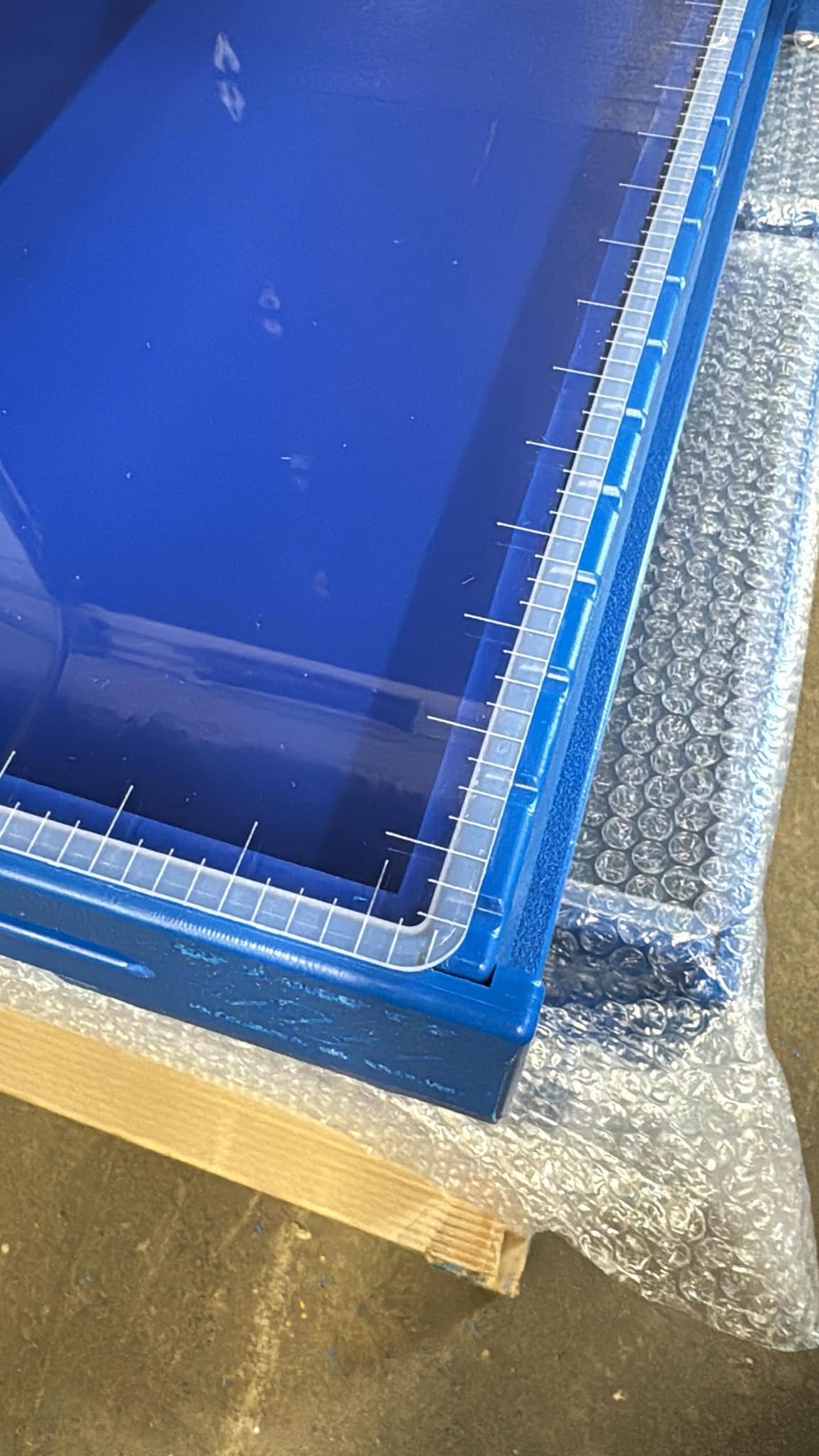 Blue plastic soap mold with clear acrylic lids sitting on a pallet with bubble wrap