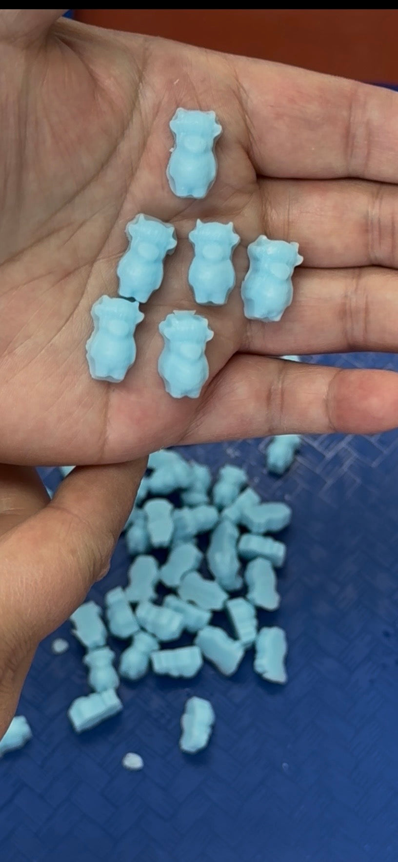 Small blue cow-shaped objects on a hand with a blue textured background