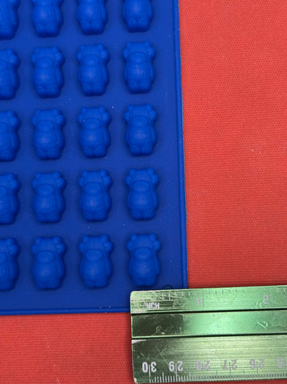 Blue silicone mold with cow shapes next to a ruler on a orange surface
