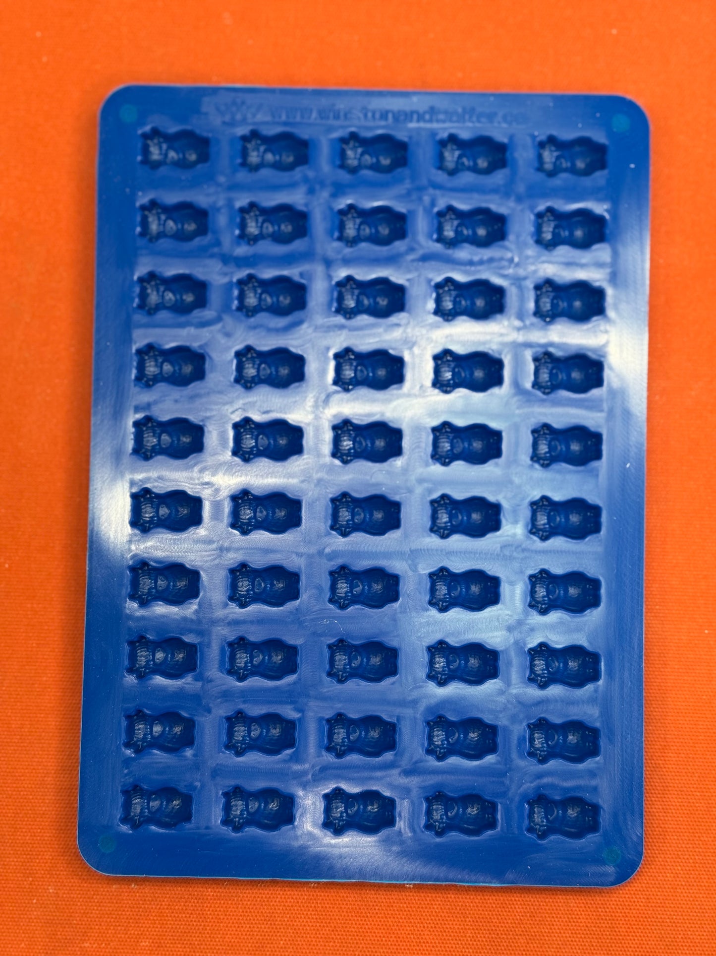 Blue silicone mold with multiple small cavities on an orange background