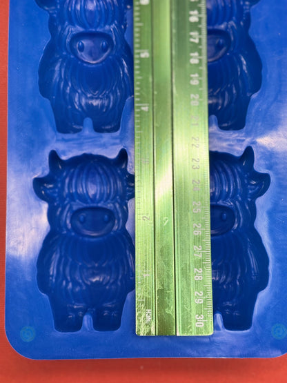 Blue mold with cow shape and a green ruler for measurement on an orange background