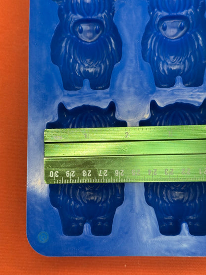 Blue mold with cow shape and a green ruler for measurement on an orange background
