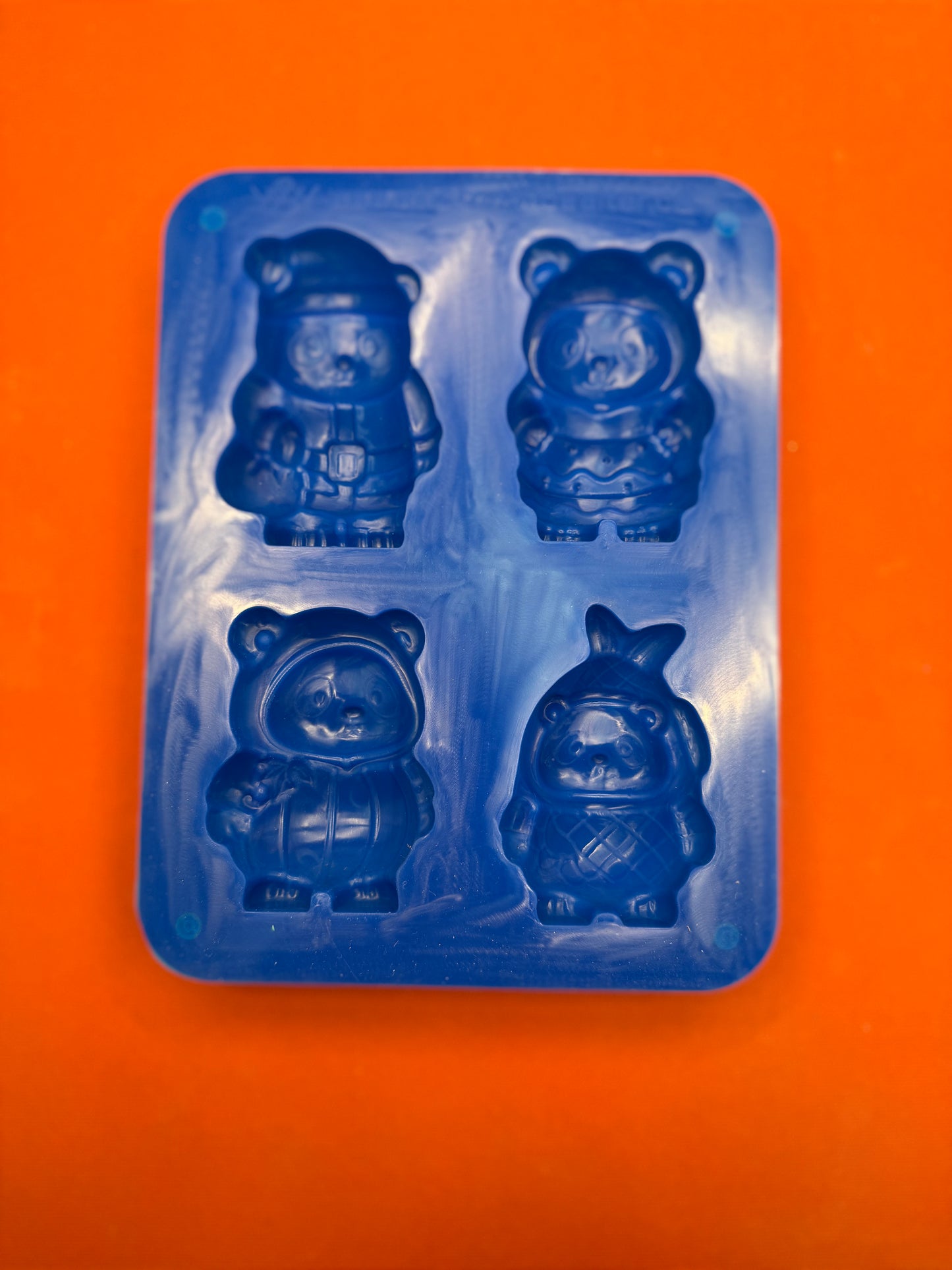 Blue silicone bear-shaped mold on an orange background
