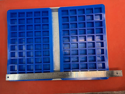 Two blue silicone mold with square compartments on an orange background, measured by a ruler.