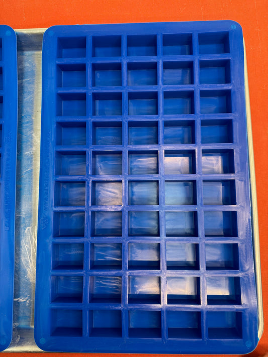Blue silicone mold with square compartments on an orange background