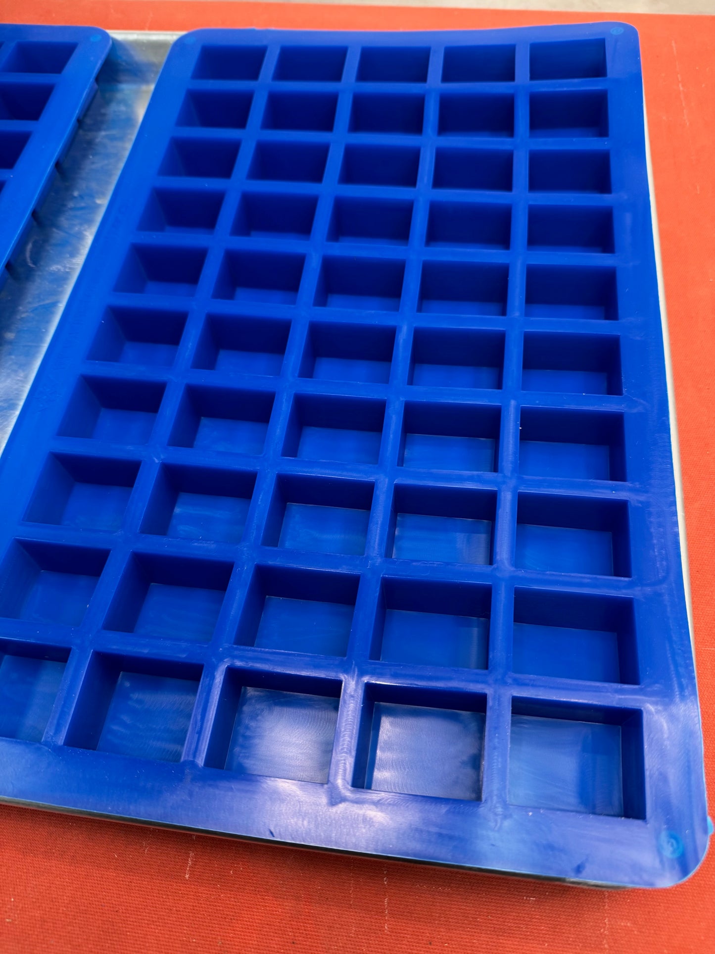 Blue silicone mold with square compartments on an orange background, 
